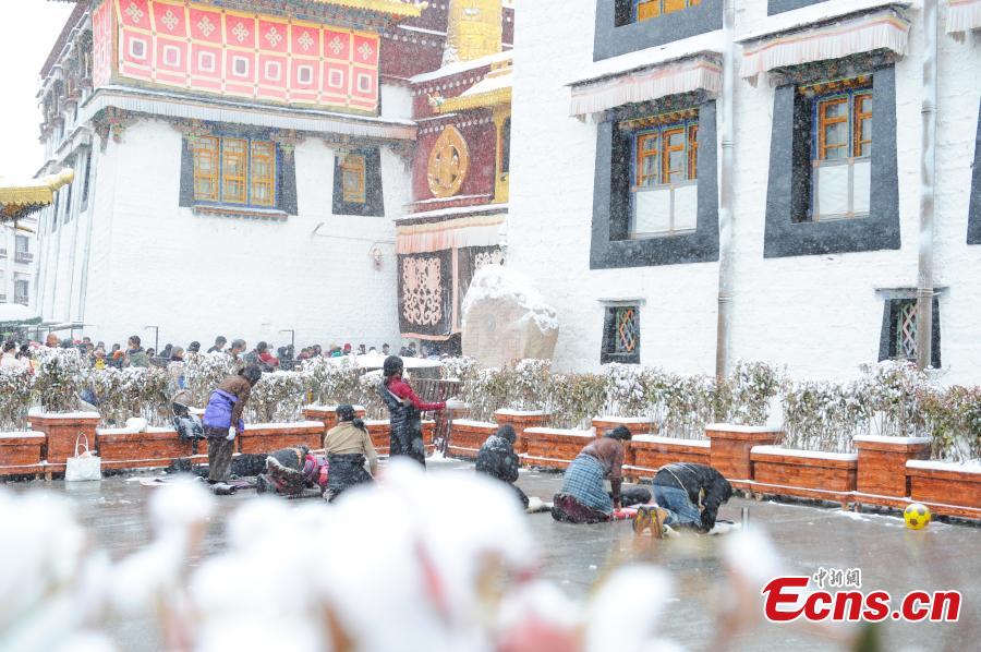 Θιβετιανοί προσκυνητές προσεύχονται μπροστά στον ναό Τζοκάνγκ μετά από χιονόπτωση στη Λάσα, στην αυτόνομη περιοχή Σιζάνγκ (Θιβέτ) της νοτιοδυτικής Κίνας, 18 Ιανουαρίου 2024. (Φωτογραφία/China News Service)