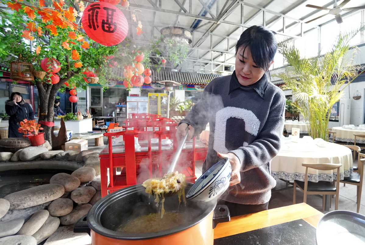 Μια γυναίκα ετοιμάζει φαγητό σε ένα εστιατόριο με τοπικά αγροτικά προϊόντα στην περιοχή Ντασίνγκ του Πεκίνου στις 22 Ιανουαρίου. [Φωτογραφία/Xinhua]