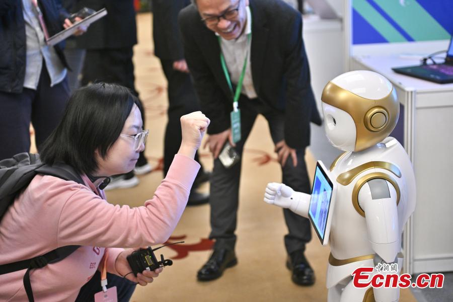 Επισκέπτρια αλληλεπιδρά με ένα ρομπότ που αναπτύχθηκε για να είναι συνοδός, στον Διαγωνισμό Ανθρωπόμορφων Ρομπότ που πραγματοποιήθηκε στην Οικονομική-Τεχνολογική Περιοχή Ανάπτυξης του Πεκίνου, 13 Μαρτίου 2024. (Φωτογραφία: China News Service)